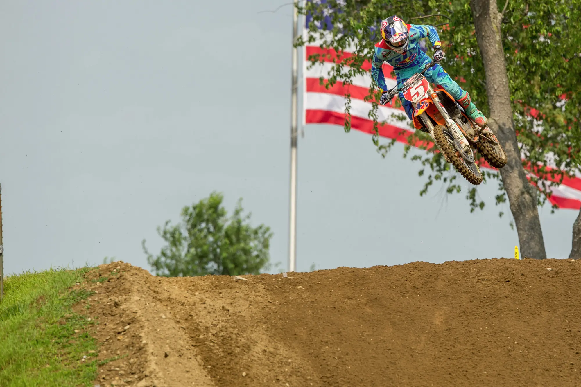 Professional motocross racer launching past an American flag