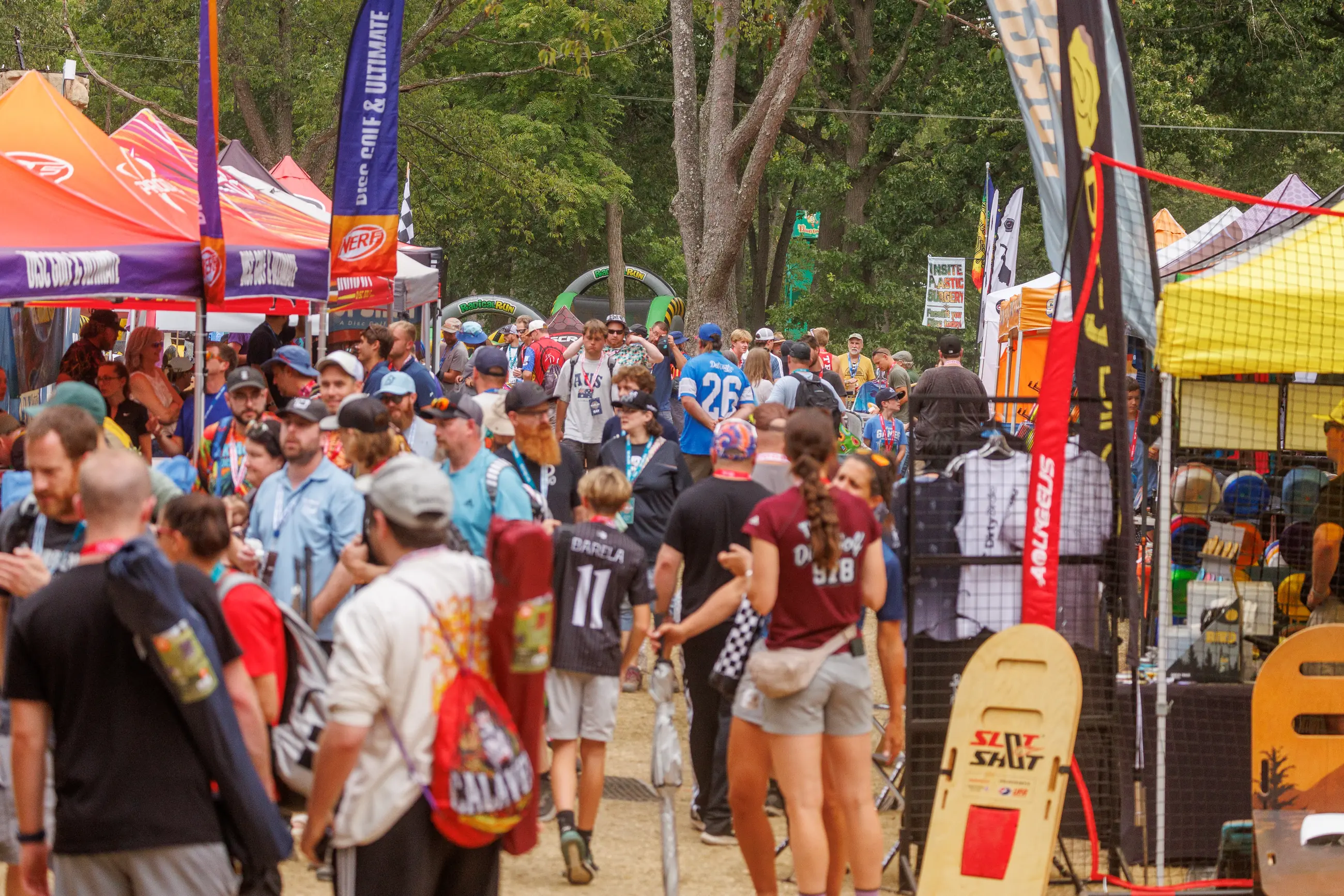 Disc golf event vendor village with spectators and sponsor displays